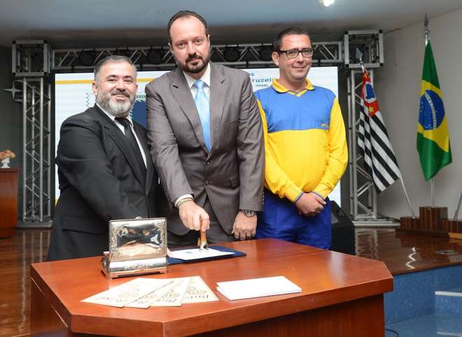 Valdir Euclides Buffo Junior usa o carimbo em homenagem ao jornal ao lado de Sebastião de Souza e Ricardo Pimentel, ambos dos Correios - ERICK PINHEIRO