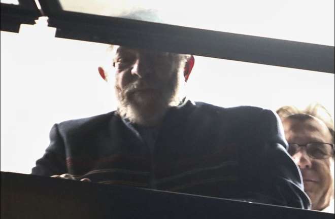 Em vários momentos nas últimas horas, Lula foi à janela acenar para os militantes - MIGUEL SCHINCARIOL / AFP