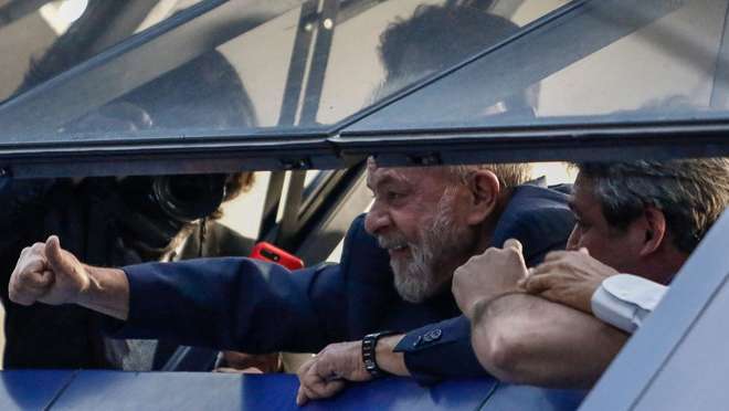 Lula acena, da janela, a militantes que cercam o Sindicato dos Metalúrgicos do ABC - MIGUEL SCHINCARIOL / AFP